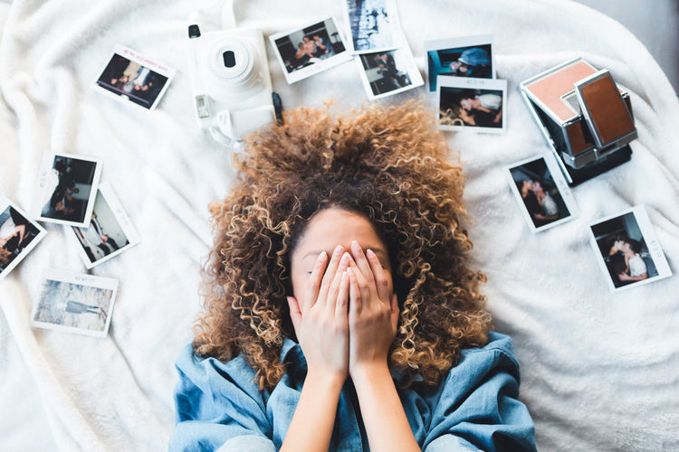 curly hair girl with hands over her face surrounded by photos